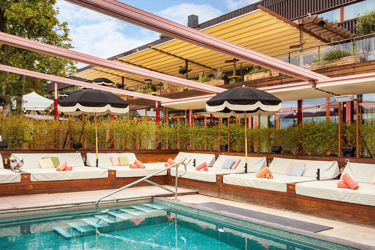 Ellery Beach House outdoor pool with cabanas and lush surroundings